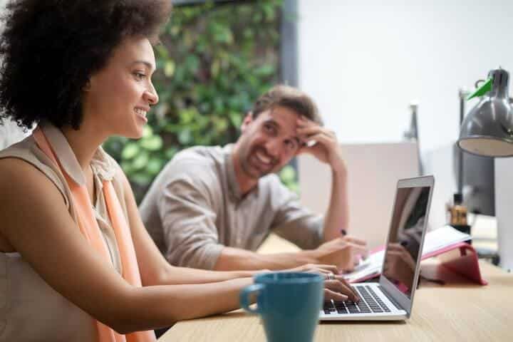 Man and woman sitting at a table smiling and using the free email checker from ZeroBounce