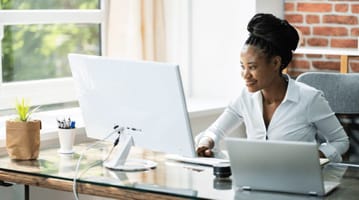 Picture of African-American young woman working at desktop computer on creating B2B email marketing campaigns.