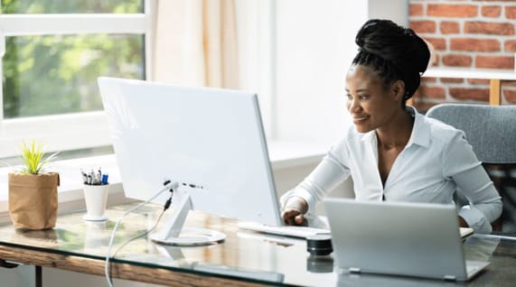 Picture of African-American young woman working at desktop computer on creating B2B email marketing campaigns.