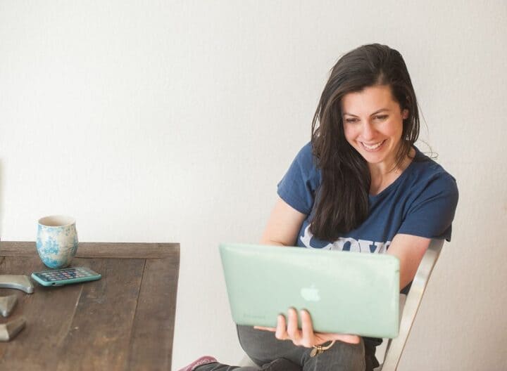 woman looking at her laptop smiling at the personalized subject line of an email. 